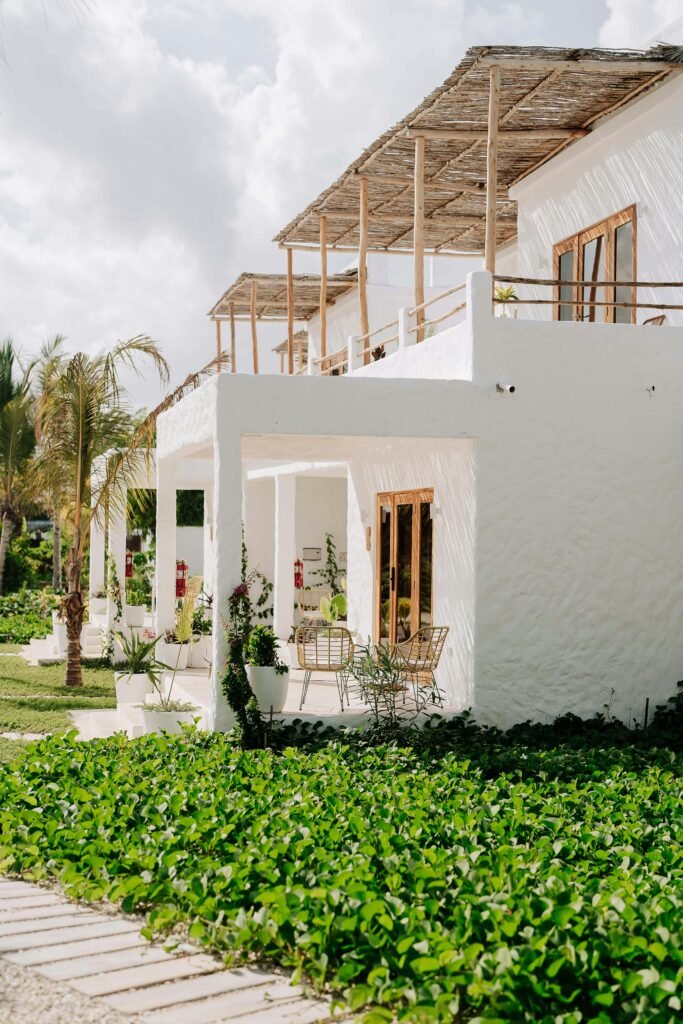 Charming white villas with outdoor seating, surrounded by vibrant greenery in Jambiani, Tanzania.