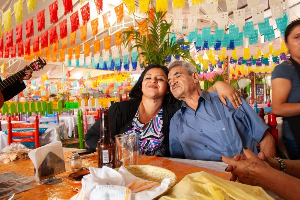 Family enjoying a festive celebration at a colorful Mexican restaurant with music and decorations.